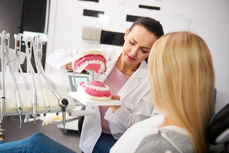 female dentist showing patient the artificial dent EW9B8QG