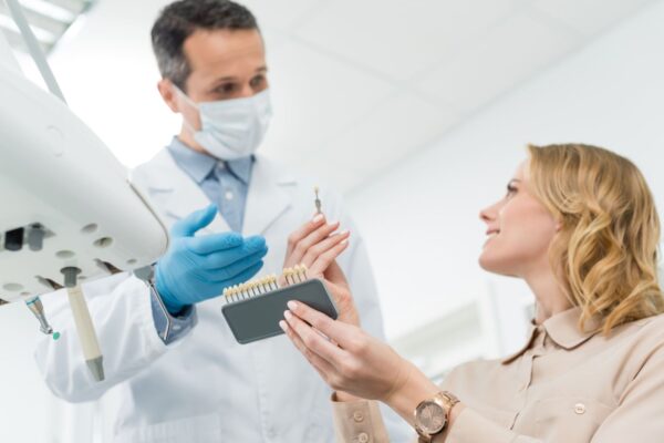 doctor-showing-tooth-implants-to-female-patient-in-2022-12-16-17-54-11-utc